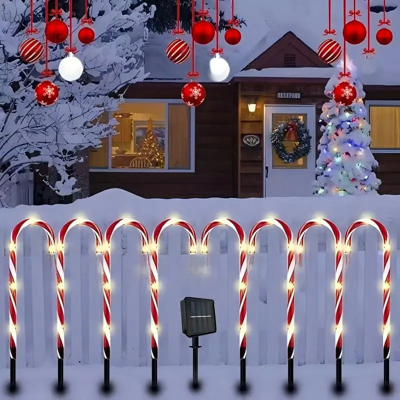 bengalas de natal iluminadas enfileiradas em cerca branca com painel solar