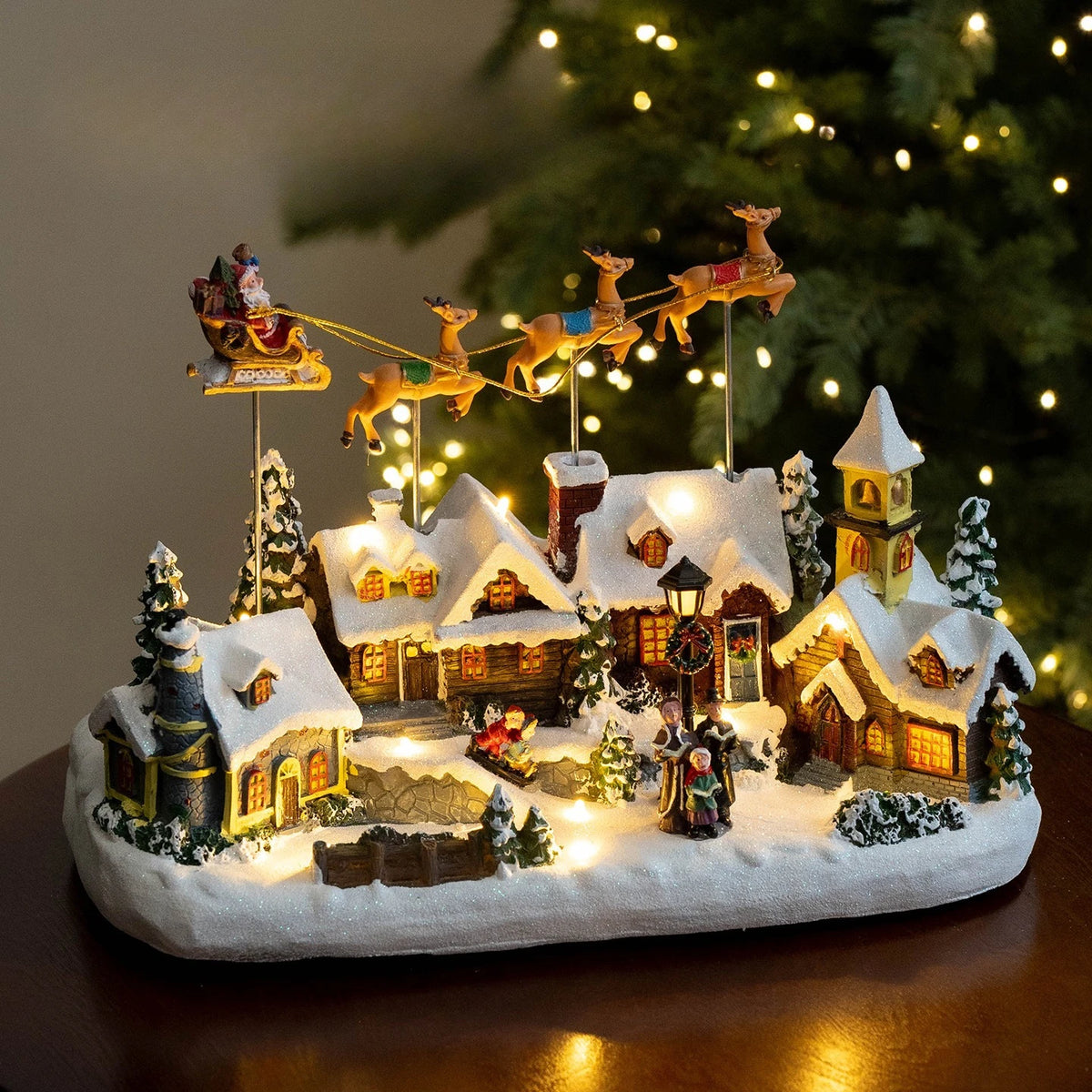 vila de natal iluminada com trenó do papai noel e renas sobre casinhas com neve